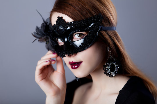 Young redhead woman in carnival mask
