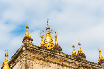 Fototapeta premium Pagodas with golden tips at the top of the Manuha temple in Bagan, Myanmar. Close-up.