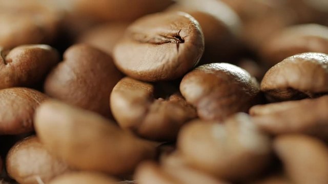 Rotating roasted coffee beans rotating on table, macro shot, slow motion.