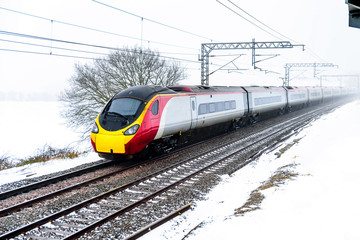 Cloudy foggy winter day view of Train on UK Railroad in England. Emma storm railway landscape.