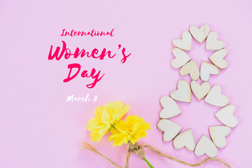 Happy International Women's Day message with beautiful yellow flowers and wooden heart on pink background. Womens Day concept.