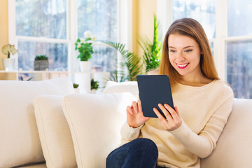 Young woman reading with an e-reader in a large interior room