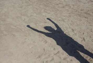 Shadow of man doing socialism sign on sand background. Raised fist is a symbol of solidarity and support. It is also used as a salute to express unity, strength, defiance, or resistance.