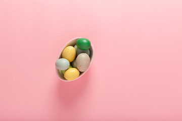 Painted Easter eggs in a basket on a pink background