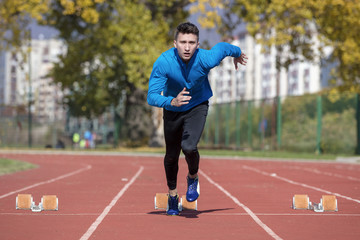 Fototapeta premium Man runner in blue shirt and shorts and sport shoes in steady position before run at start of race.