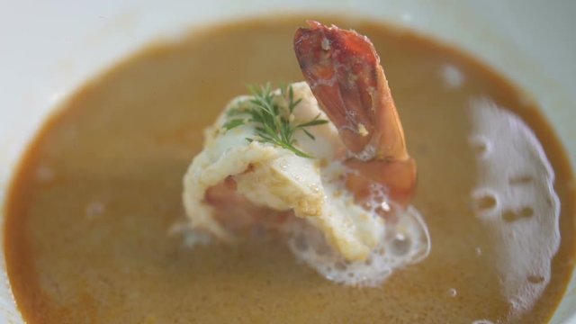 Closeup hot steaming schrimp soup in the porcelain bowl