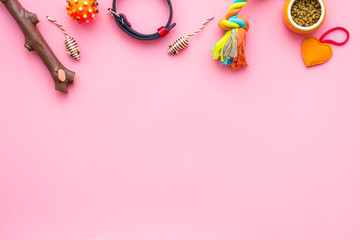 Pet accessories. Toys near bowls with animal feed, collar on pink background top view copy space