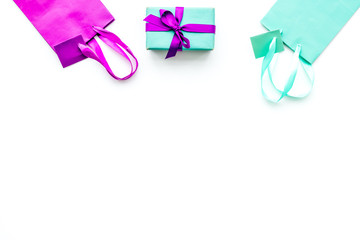 Gift box and colorful paper bag on white background top view copy space