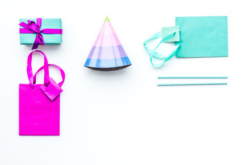 Birthday party accessories. Gift box, paper bag, party hat on white background top view copy space