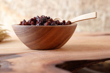 Raisin in bowl on wooden background.