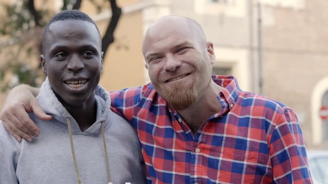 interracial friendship: young black and white men hugging and laughing