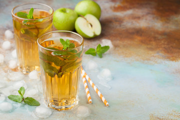 Two glasses of green Apple juice with mint and ice on an old rusty table. Soft drink on a blue background. With copy space
