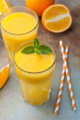 Two glasses with freshly squeezed orange juice and mint on an old rusty blue background