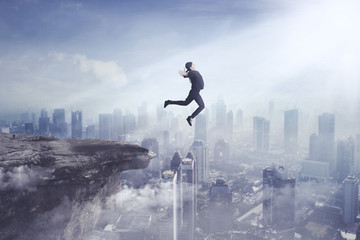 Young businesswoman jumping off a cliff