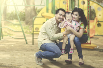 Fototapeta premium Young family posing together at playground.