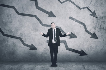 Confused caucasian businessman with declining charts on the wall