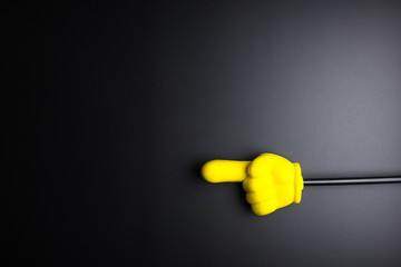 Yellow plastic hand pointing on black background with copy space.