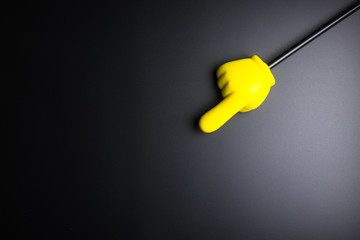 Yellow plastic hand pointing on black background with copy space.