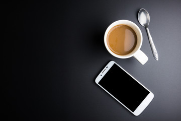 Fototapeta na wymiar White coffee cup and smartphone on black background with copy space.