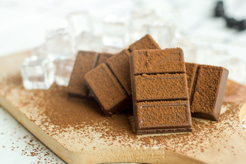 Close up a chocolate bar and ice cubes on wooden plate