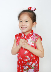 Smiling little asian girl in cheongsam isolated on white background during traditional chinese new year festival.