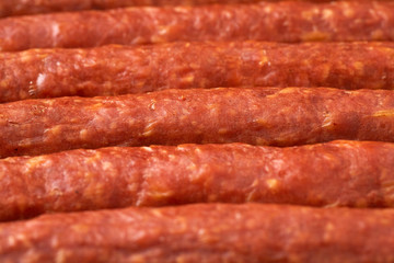 Some thin smoked sausages in a row close-up.