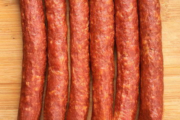 Thin smoked sausage on a wooden background. Close-up.