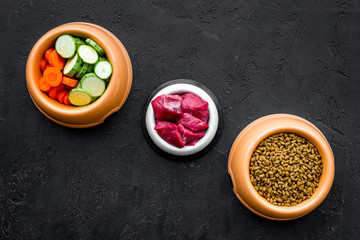 Ingredients for dry pet food. Meat and vegetables zucchini and carrot on black backgroud top view copy space