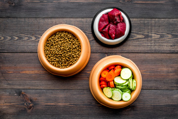 Ingredients for dry pet food. Meat and vegetables zucchini and carrot on dark wooden backgroud top view copy space