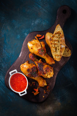Fried spicy chicken legs on the wooden background with the sauce