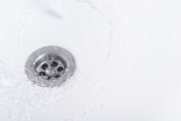 close-up of how water drains into a white washbasin, top view