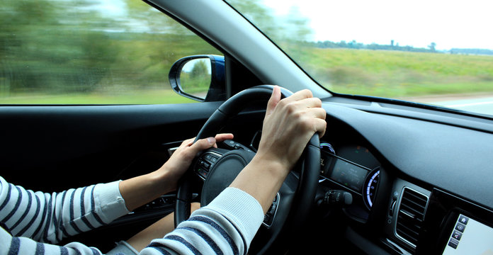 Wrong position of man’s hands on the steering wheel inside fast moving vehicle
