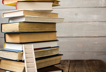 ladder on pile of old books on wooden background