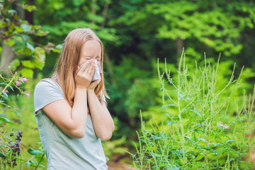 Young woman sneezes because of an allergy to ragweed