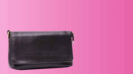 Black leather clutch on pink color background