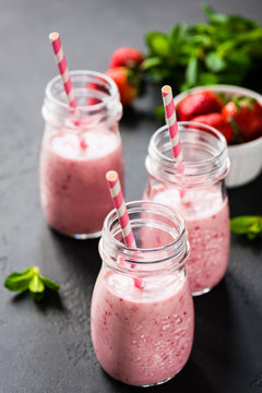 Strawberry smoothie in bottles with drinking straw. Selective focus. Healthy lifestyle, fitness, detox, dieting, clean eating, vegan, vegetarian concept
