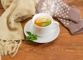 Tea with lemon and mint against of woolen mittens, scarf