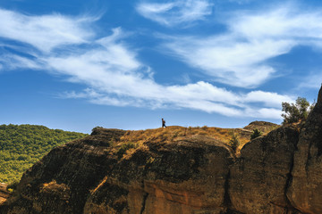 Man with backpack on the edge of the rock look on the monasteries of Meteora