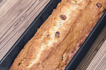 Homemade rectangular traditional cupcake with raisins in baking dish on the brown wooden background. Closeup, selective focus