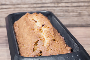 Homemade rectangular traditional cupcake with raisins in baking dish on the brown wooden background. Closeup, selective focus
