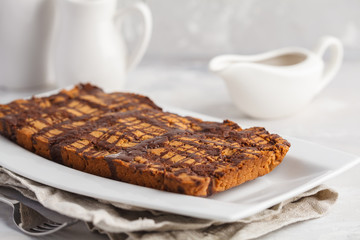 Vanilla vegan aquafaba cake with chocolate glaze in a white dish. Healthy vegan food concept.
