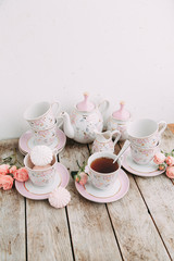 tea set in composition with flowers and marshmallows. Coffee mug on a saucer, a teapot and a sugar bowl. Filmed in the interior