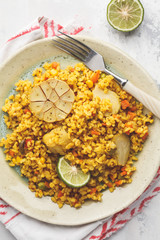 Curry bulgur with vegetables in white plate, top view. Healthy vegan food concept.