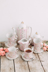 tea set in composition with flowers and marshmallows. Coffee mug on a saucer, a teapot and a sugar bowl. Filmed in the interior