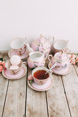 tea set in composition with flowers and marshmallows. Coffee mug on a saucer, a teapot and a sugar bowl. Filmed in the interior