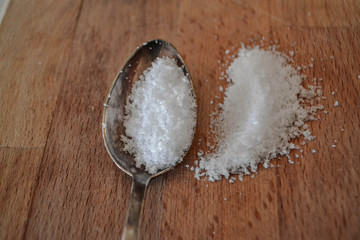 Fototapeta na wymiar Closeup of sea salt in silver spoon at wooden background 