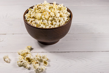 Bowl with popcorn on wooden table