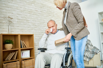 Portrait of female psychiatrist consoling crying senior man in wheelchair during therapy session,...