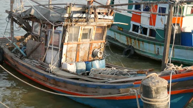 Old wooden half-ruined and wrecked ship is moored on a fishing dock
