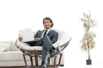 modern businessman with a laptop sitting in a stylish comfortable chair